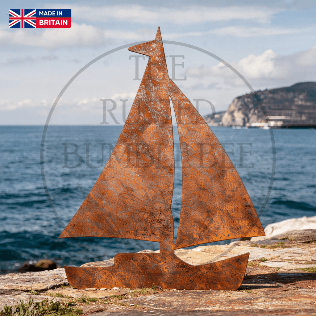 Rust-colored metal sailboat sculpture on a rocky outcrop with ocean and sky in the background